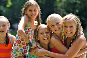 four girls at camp enjoy the slip n slide