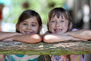 Two friends look over fence post at summer camp
