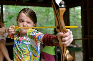 girl at camp aims at target in archery