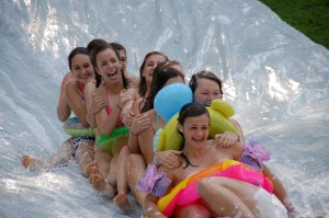 Older girls enjoy sliding down the slip n slide at camp.