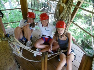 Three girls get ready to climb the high ropes course at Camp Illahee.