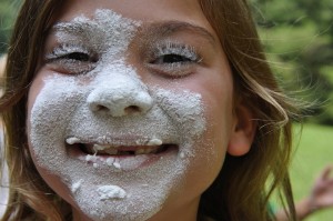 Girl with flour on face and BIG smile at camp