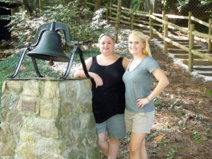 Two Illahee alumnae pose by the bell.