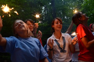 Hillbrook JC's sing with sparklers at campfire.