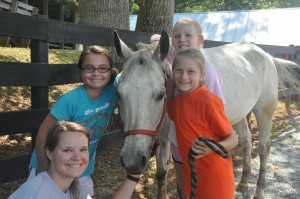 Illahee summer campers and counselor pose with white horse.
