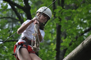 Summer camp girl negotiates high ropes course.