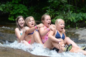 Four summer campers in train go down sliding rock.