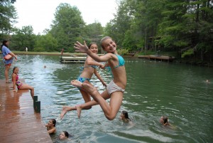 Two summer camp girls jump into the lake