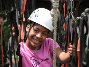 Summer camper navigates the ropes course at Camp Illahee.