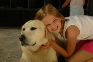 A summer camper gives the camp dog a hug.