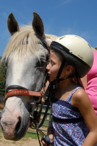 A young Illahee Summer Camp girl gives a white pony a kiss.