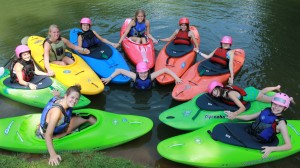 Colorful summer camp kayakers pose in a circle.