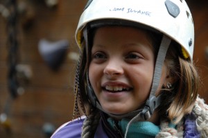 Camp girls smiles as she waits fro her turn on the Camp Illahee high ropes course.