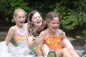 Three camp girls sliding down sliding rock.