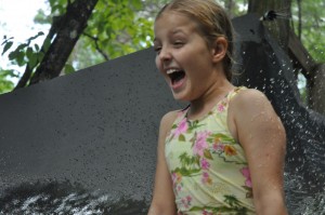A camp girl with a grin on her face at the top of the water slide.