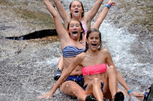 Three Illahee Summer Campers with arms raised head down Sliding Rock.