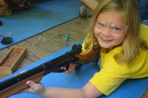 A summer camper looks up from her air rifle during riflery activity at Camp Illahee Summer Camp for Girls.