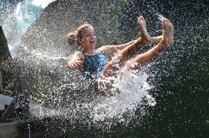 Girl surrounded by water droplets leaves the end of a giant water slide.