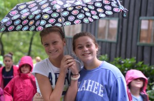 Two campers smile for the camera under a polka dotted umbrella.
