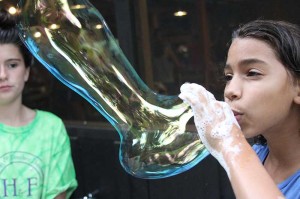 A camp illahee camper blows a giant soap bubble.