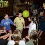 Camp Illahee counselors holding hands during orientation, keeping a yellow balloon in the air.