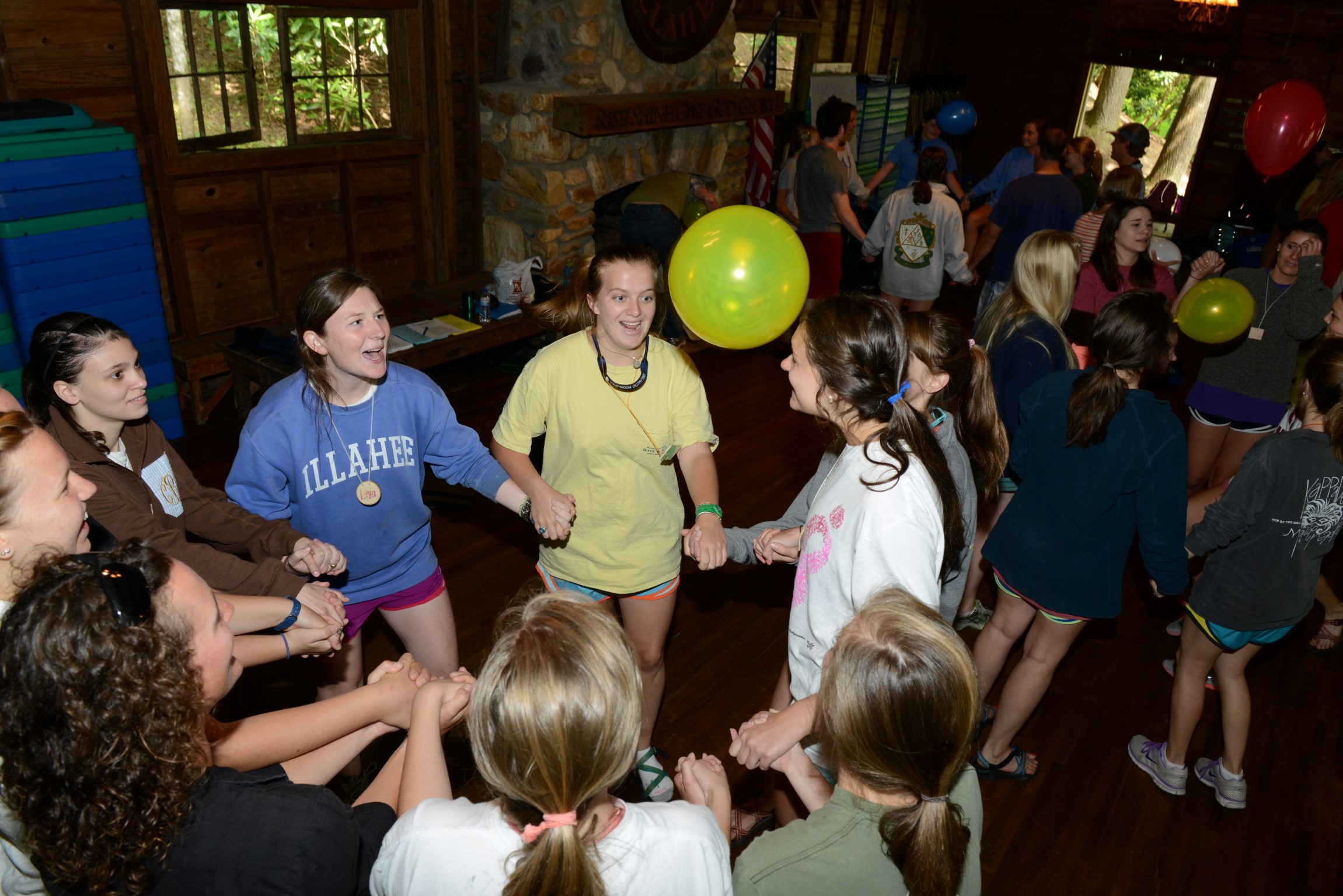 Camp Illahee counselors holding hands during orientation, keeping a yellow balloon in the air.