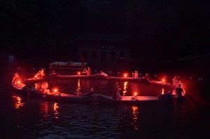 Canoes in a circle, lit by candles.
