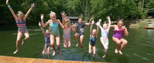 Girls jumping off pier into lake