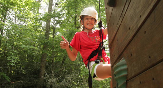 Girl giving thumbs up on rockclimbing course
