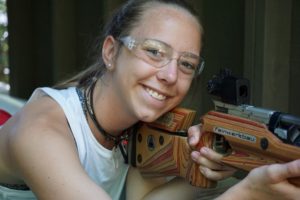 A Camper smiles as she looks up from her air rifle.