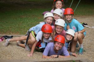 Helmet-clad Illahee campers pile on top of their belayer, counselor.