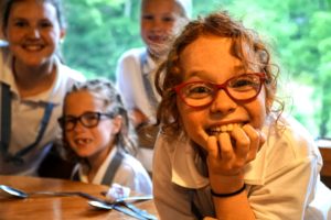 A red-headed camper hams it up at the dining hall table with cabin mates.