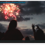 A fireworks shell bursts on a clear night as campers reach for the sky in silhouette.