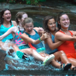 Campers from Camp Illahee heading down Sliding Rock in a train.